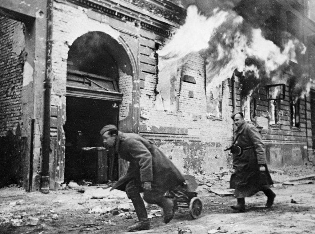 Советские пулеметчики продвигаются вдоль горящего дома на улице Берлина, апрель 1945 г. Источник фото: http://waralbum.ru